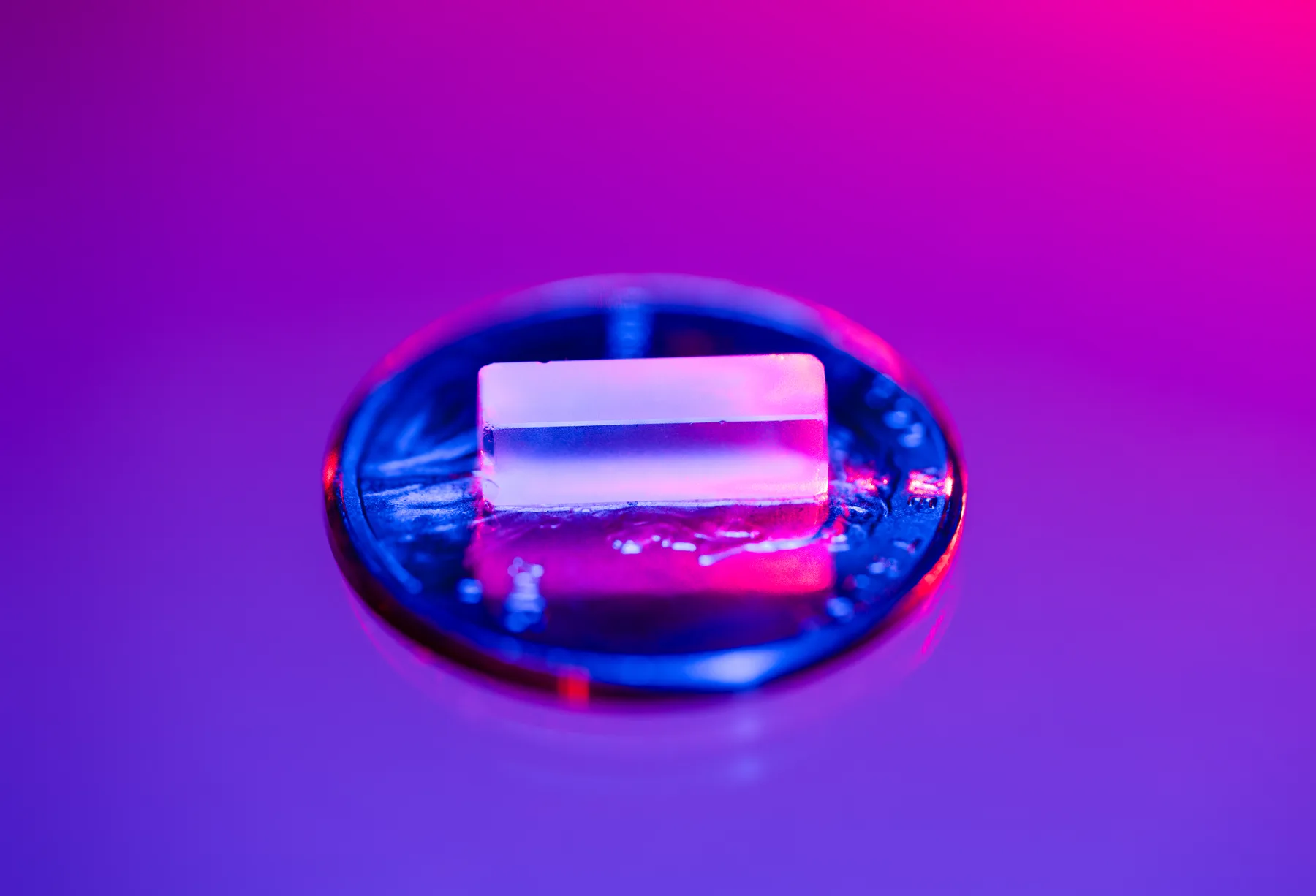 An illuminated crystal glowing pink and blue in the laboratory